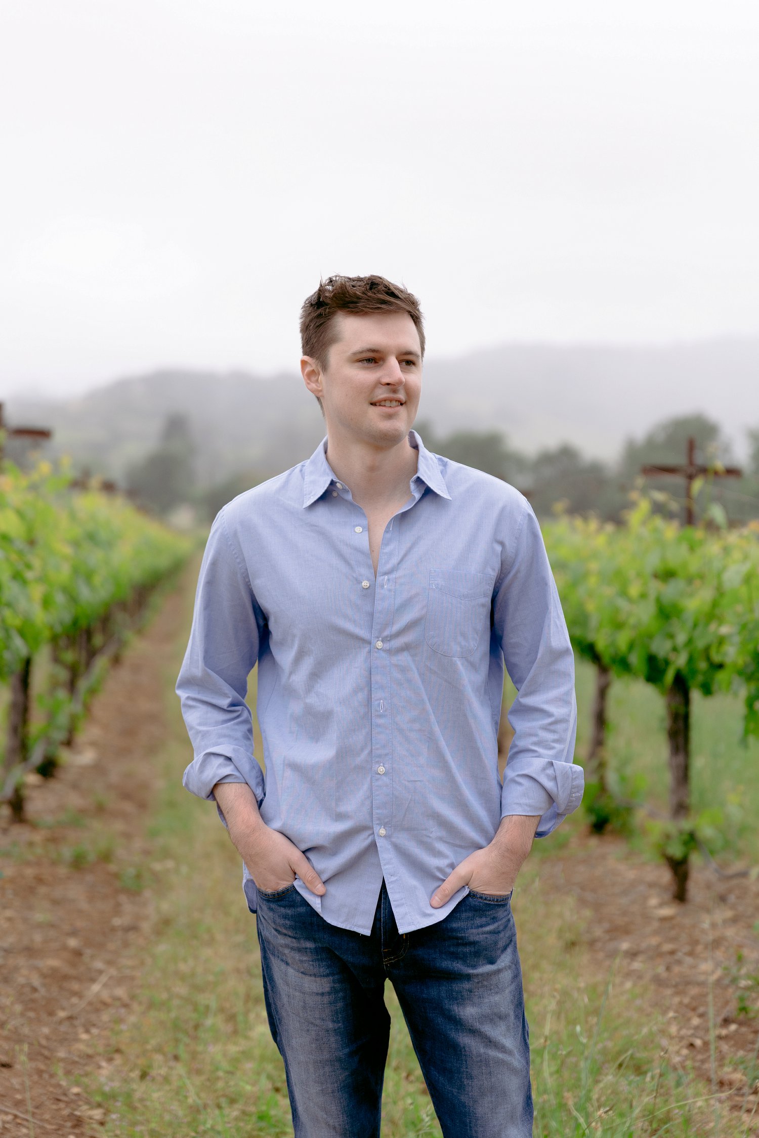 A handsome groom posing in the rows of grapevines during an overcast Chateau St Jean Winery engagement session.
