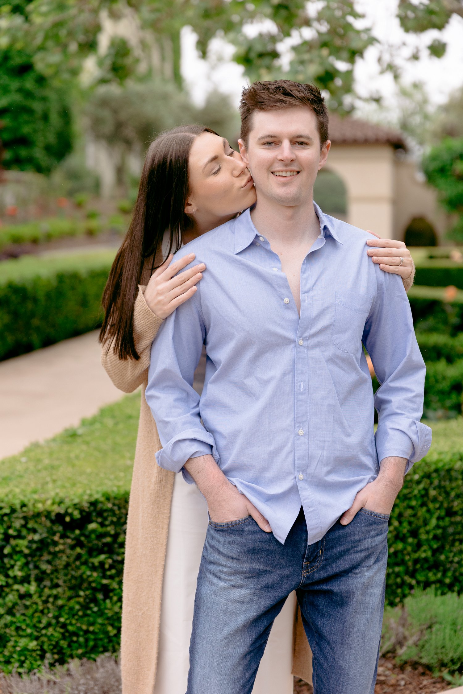 A romantic embrace and kiss on the cheek during a fairytale themed Chateau St Jean Winery engagement shoot.