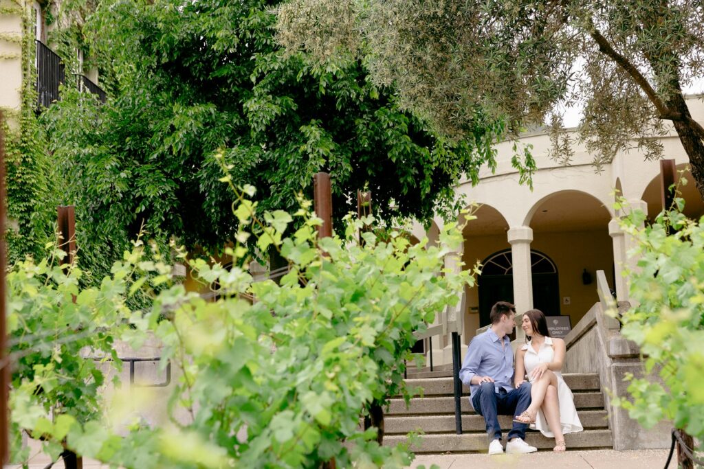 a couple sitting in front of Stunning architectural details and European styling at a fairytale themed Chateau St Jean Winery engagement location